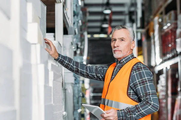 Trabajador senior que utiliza tableta digital en el almacén - foto de stock