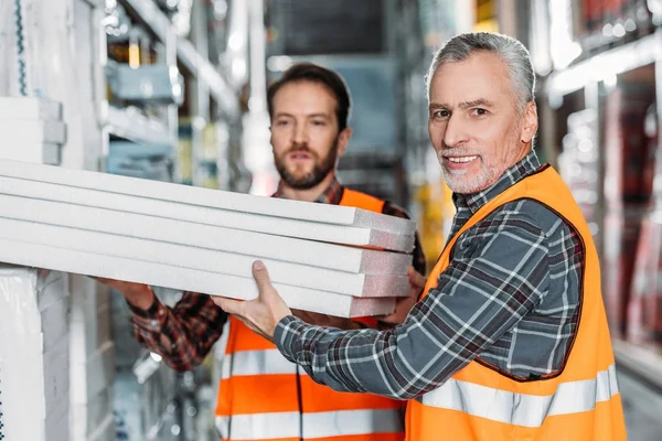 Dos trabajadores masculinos que sostienen la espuma de poliestireno en stock de envío - foto de stock