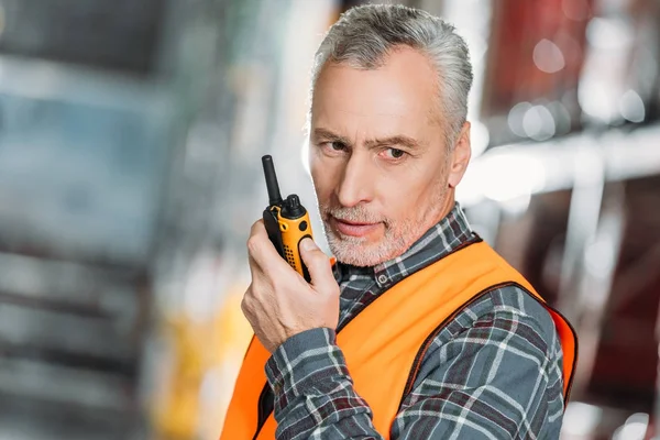 Trabajador senior usando walkie talkie en stock de envío - foto de stock