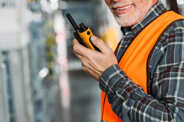 Vista recortada del trabajador senior usando walkie talkie en el almacén - foto de stock