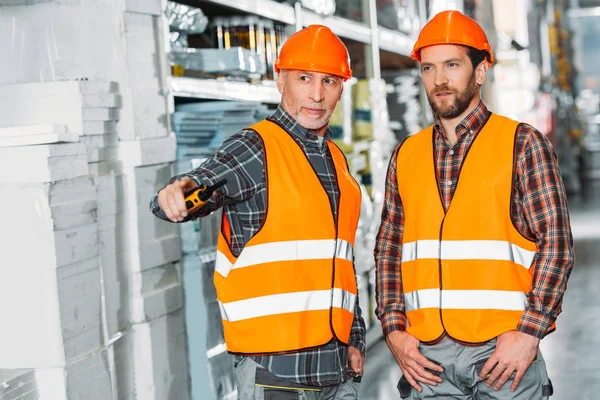 Dos trabajadores masculinos sosteniendo walkie talkie en el almacén - foto de stock