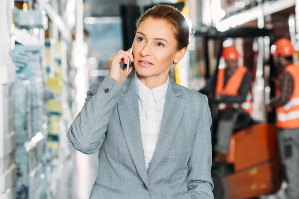 Femme d'affaires parlant sur smartphone dans le stock d'expédition — Photo de stock