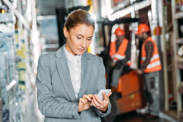 Geschäftsfrau nutzt Smartphone im Warenlager — Stockfoto