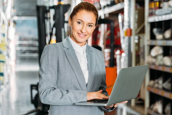 Femme d'affaires utilisant un ordinateur portable dans le stock d'expédition — Photo de stock