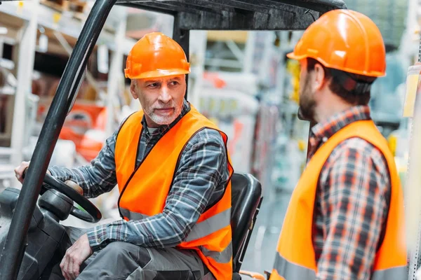 Worker and his senior colleague working with forklift machine in shipping stock — Stock Photo