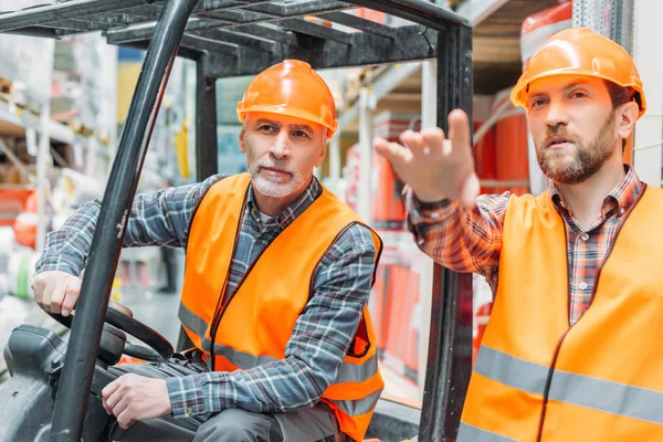 Arbeiter und sein älterer Kollege arbeiten mit Gabelstapler-Maschine im Lager — Stockfoto