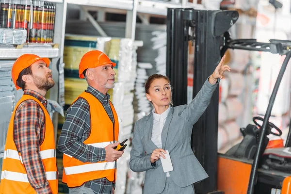 Женщина-инспектор показывает что-то работникам склада — Stock Photo