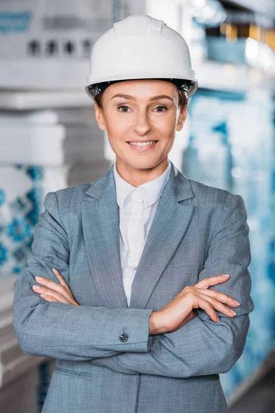 Female inspector in hardhat posing with crossed arms in storage — Stock Photo