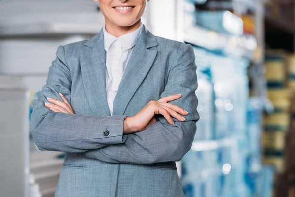 Cropped view of female posing with crossed arms in warehouse — Stock Photo