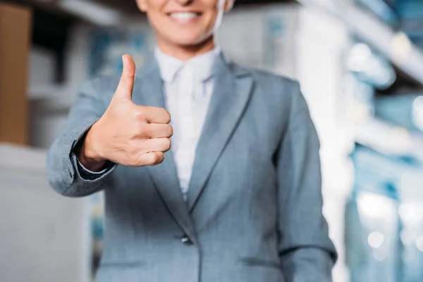 Cropped view of female inspector showing thumb up in warehouse — Stock Photo