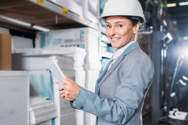 Female inspector in helmet using digital tablet in warehouse — Stock Photo