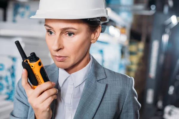 Ispettore donna in casco con walkie talkie in magazzino — Foto stock