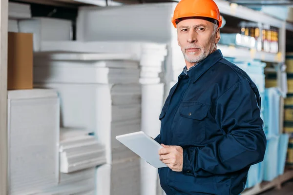 Trabajador masculino senior en casco con tableta digital en stock de envío - foto de stock