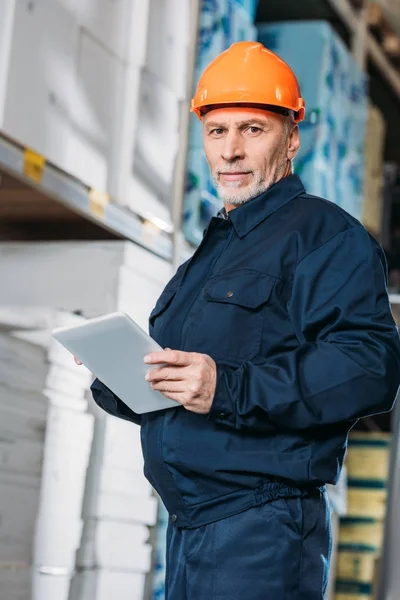 Senior male worker in helmet with digital tablet in shipping stock — Stock Photo