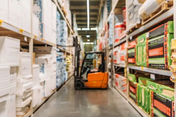 Vista sfocata di carrello elevatore e scaffali con scatole in magazzino — Foto stock