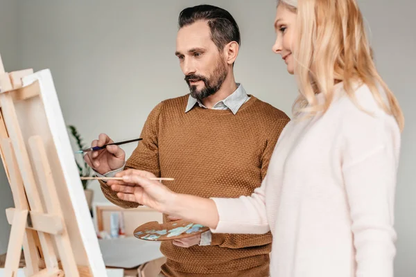 Side view of smiling mature students of art class painting together — Stock Photo