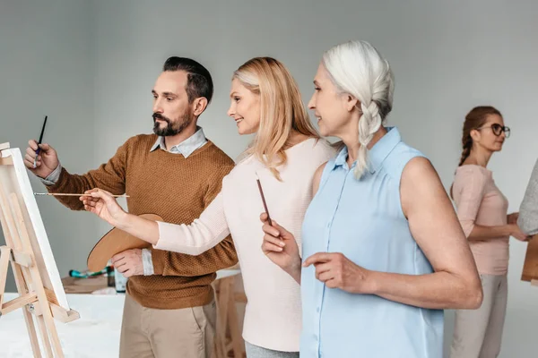 Seitenansicht reifer Künstler beim gemeinsamen Malen im Kunstunterricht — Stockfoto