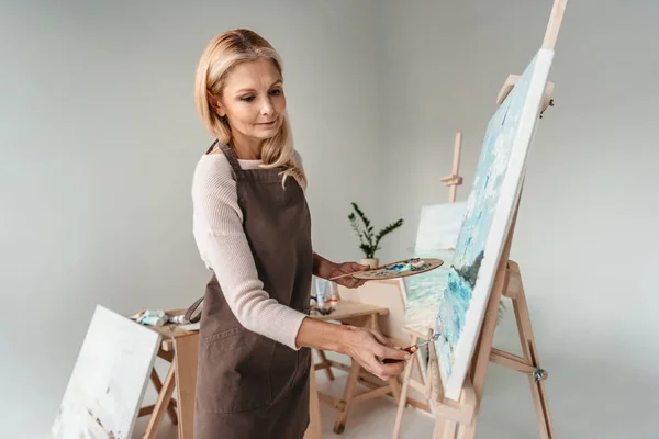 Красиві зріла жінка в фартух живопис на станковий в мистецтві клас — стокове фото