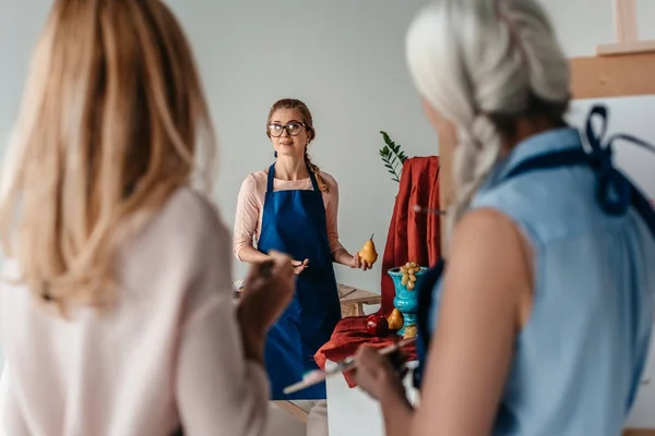 Back view of senior women looking at artist holding art tools for still life in art studio — Stock Photo