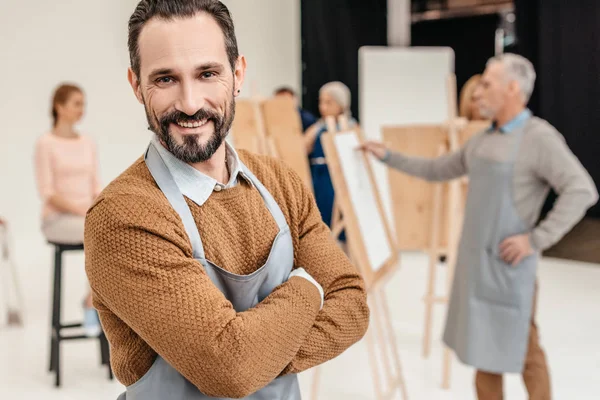 Bello artista maturo sorridente alla macchina fotografica in studio d'arte — Foto stock