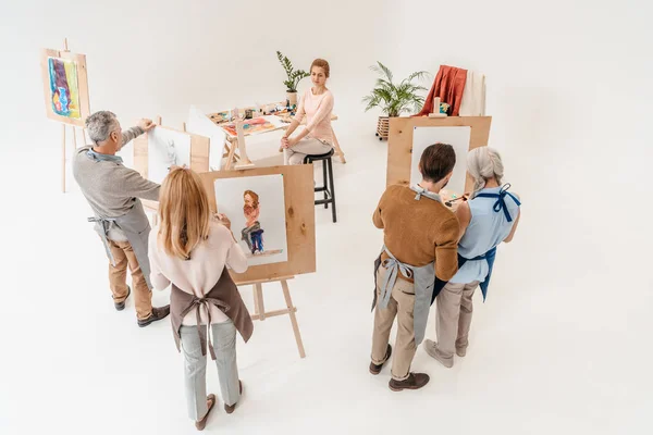 Blick aus der Vogelperspektive: Senioren malen während des Kunstunterrichts auf Staffeleien — Stockfoto