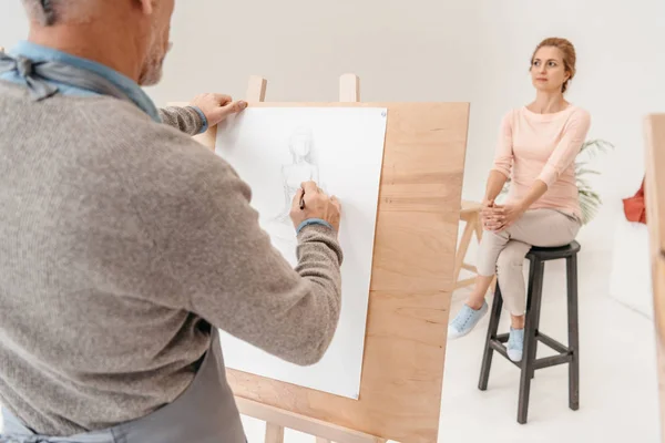 Corte tiro de homem sênior pintura no cavalete e mulher posando no estúdio de arte — Fotografia de Stock