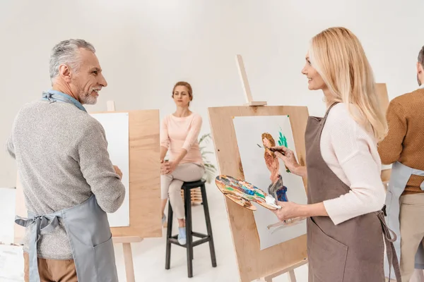 Senior-Künstler malen und betrachten einander im Kunstatelier — Stockfoto