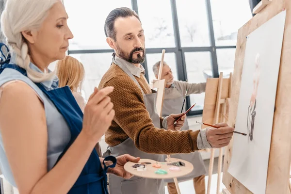 Male and female adult students painting together at art class — Stock Photo