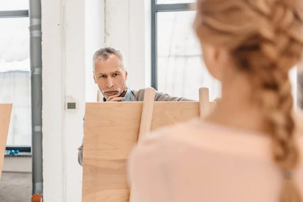 Selective focus of senior man painting on easel and woman posing in art studio — Stock Photo