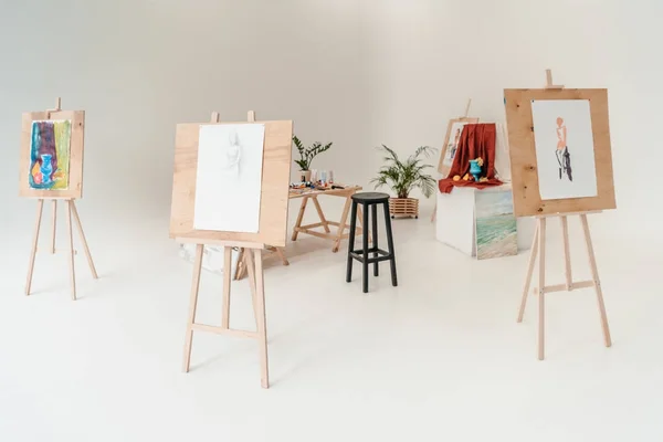 Easels with paintings in empty art studio — Stock Photo