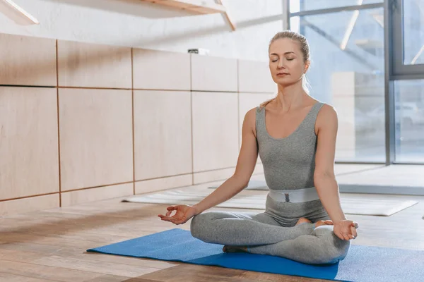 Mujer meditando con los ojos cerrados en pose de loto yoga con mudra de conocimiento — Stock Photo