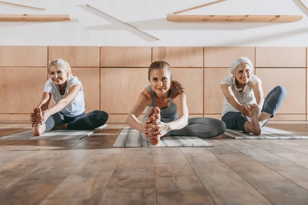 Gruppo di donne che si allungano su stuoie di yoga in studio — Foto stock