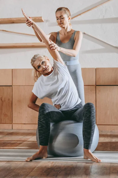 Mujeres mayores y entrenador de ejercicio en pelotas de fitness en el estudio — Stock Photo