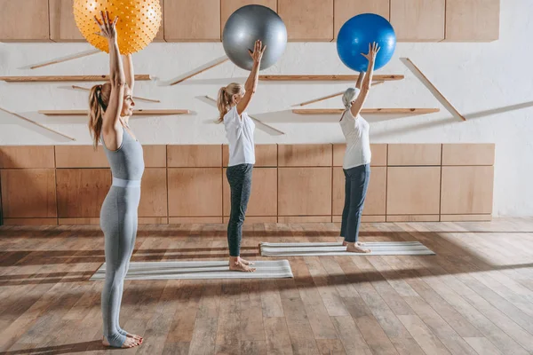 Grupo de mujeres haciendo ejercicio con pelotas de fitness en el estudio - foto de stock