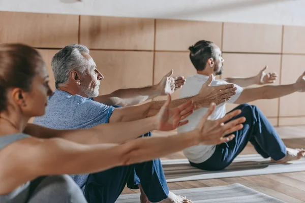 Grupo de pessoas praticando ioga em tapetes em estúdio — Fotografia de Stock