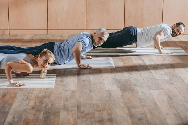 Instructora de ejercicios con hombres maduros en colchonetas de yoga en clase de entrenamiento - foto de stock