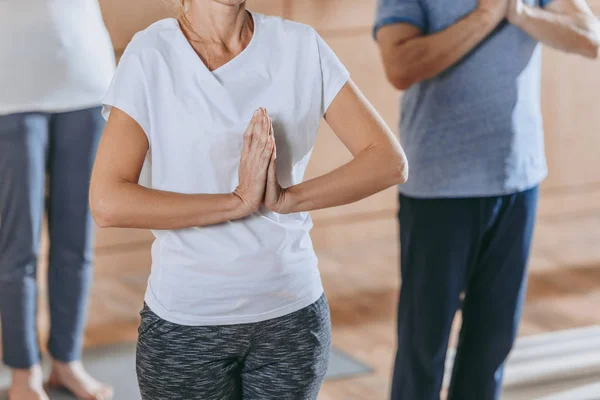 Foto recortada de personas maduras con signo namaste practicando yoga juntas - foto de stock