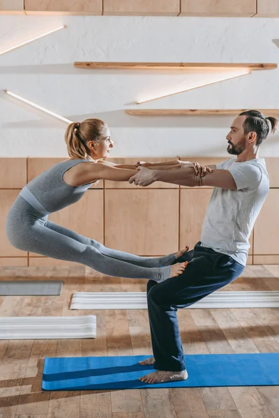 Middle aged couple practicing yoga together in fitness studio — Stock Photo