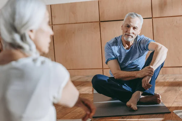 Selective focus on senior people in sportswear sitting on yoga mats at training class — Stock Photo