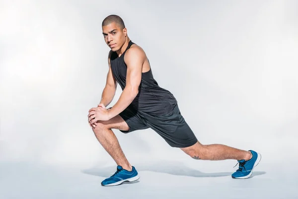 African american sportsman stretching legs and looking at camera — Stock Photo