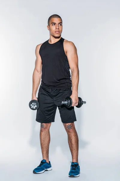 Serious african american sportsman standing with dumbbells — Stock Photo