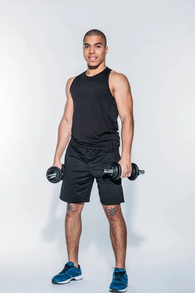 Smiling african american sportsman standing with dumbbells — Stock Photo