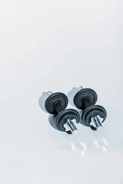 Overhead view of two black dumbbells on white floor — Stock Photo