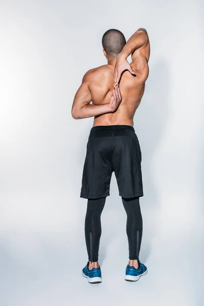 Visão traseira do esportista afro-americano que se estende para trás — Fotografia de Stock