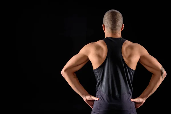 Vista trasera del deportista americano africano musculoso parado aislado en negro - foto de stock