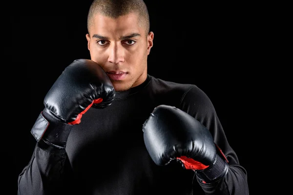 Jeune boxeur afro-américain en gants noirs isolé sur noir — Photo de stock