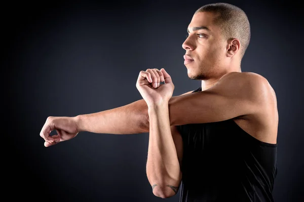 Jeune sportif afro-américain étirant les bras sur noir — Photo de stock