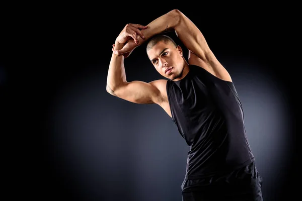 Beau sportif afro-américain faisant flexion latérale avant l'entraînement sur noir — Photo de stock