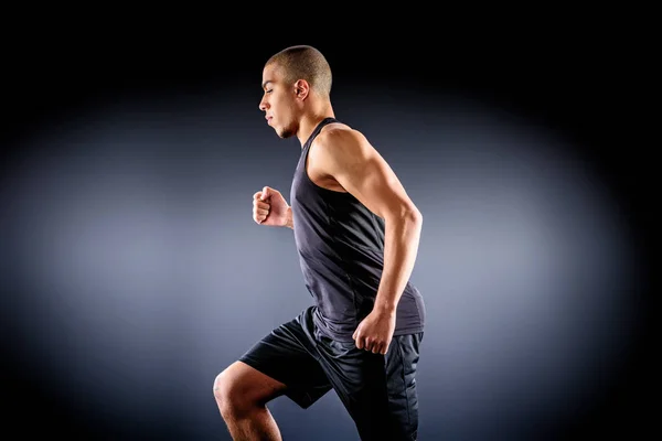 Side view of african american sportsman running on black — Stock Photo