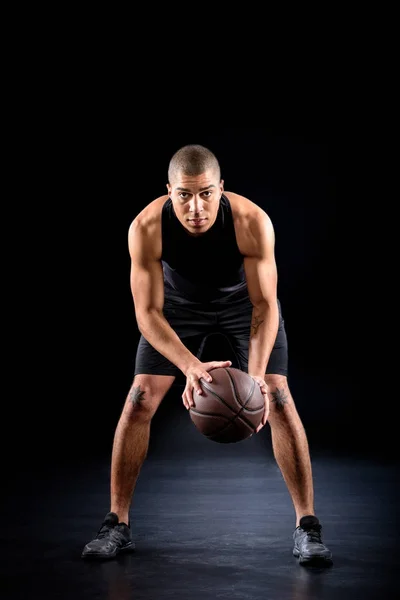 Konzentrierter afrikanisch-amerikanischer Basketballspieler mit Ball auf Schwarz — Stockfoto